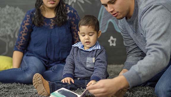 Ethnic parents reading with their toddler in a playroom